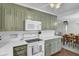 Charming kitchen featuring a microwave and white oven with olive green cabinets, tiled backsplash, and white countertops at 1406 Iroquois St, North Charleston, SC 29405