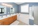 Bright bathroom featuring double sinks, a large bathtub, and natural wood cabinetry at 1433 Oakhurst Dr, Mount Pleasant, SC 29466