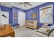 This bedroom offers a light wood crib, a cushioned bench, and bright blue walls at 1821 Mead Ln, Johns Island, SC 29455
