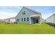 Spacious backyard with lush green grass, a covered patio, and a charming blue house, ideal for relaxation and entertainment at 2239 Macallan Blvd, Ravenel, SC 29470