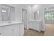 Bright bathroom featuring double vanities, white cabinets, and wood-look flooring, creating a clean and modern space at 2239 Macallan Blvd, Ravenel, SC 29470