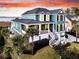 Stunning elevated home boasts coastal charm, picturesque views, and lush landscaping under a vibrant sunset sky at 2777 Oak Manor Dr, Mount Pleasant, SC 29466