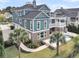 Stunning three-story teal home featuring a private pool, brick accents, a rooftop deck, and a lush landscaped yard at 2777 Oak Manor Dr, Mount Pleasant, SC 29466