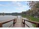 Scenic view of a wooden dock leading to a calm lake surrounded by lush trees and a blue sky at 406 Summers Dr, Summerville, SC 29485