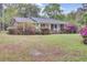 Well-kept house surrounded by lush greenery, blooming bushes, and mature trees enhancing its natural appeal at 407 Boone Hill Rd, Summerville, SC 29483