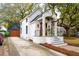 Charming white brick home with a striking black roof, complemented by a detached garage and mature landscaping at 6 Beverly Rd, Charleston, SC 29407