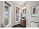 Stylish powder room with modern vanity, chic mirror, herringbone floors, and bright natural light at 6 Beverly Rd, Charleston, SC 29407
