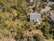 Aerial view of home nestled among trees with screened porch and spacious yard at 864 Club Cottage Rd, Edisto Beach, SC 29438