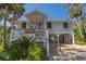 Charming raised beach house with inviting front porch, shaded parking, and lush tropical landscaping at 864 Club Cottage Rd, Edisto Beach, SC 29438