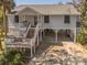 Elevated coastal home featuring a welcoming front porch and ample covered parking underneath at 864 Club Cottage Rd, Edisto Beach, SC 29438