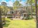 Brick home backyard with a wooden playhouse, patio, lush lawn, and mature trees, offering a private outdoor space at 8795 E Fairway Woods Cir, North Charleston, SC 29420