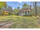 Expansive backyard featuring a custom playhouse, lush lawn and a brick home with a covered porch and a patio at 8795 E Fairway Woods Cir, North Charleston, SC 29420