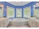 Bright bathroom with a large tub, marble floors, and dual sinks at 8795 E Fairway Woods Cir, North Charleston, SC 29420