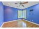 Bedroom featuring blue accent walls, hardwood floors, white trim, ceiling fan, and corner windows at 8795 E Fairway Woods Cir, North Charleston, SC 29420