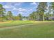 Scenic golf course view showcasing the lush green fairway and trees under a partly cloudy sky with upscale homes in the background at 8795 E Fairway Woods Cir, North Charleston, SC 29420