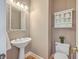 Cozy half bathroom with a pedestal sink, decorative mirror, and ample lighting at 8795 E Fairway Woods Cir, North Charleston, SC 29420