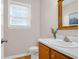 A half bathroom with stylish fixtures, a vanity, a mirror, and a window, offering a blend of functionality and aesthetic appeal at 104 Queen Mary Ct, Summerville, SC 29485