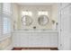 Bathroom featuring double sinks, decorative wallpaper, and white cabinets at 106 Beaufain St, Charleston, SC 29401