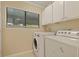 Bright laundry room features a window, washer, dryer, and white cabinetry above the appliances at 1120 Hidden Cove Dr # I, Mount Pleasant, SC 29464