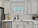 Close-up of a bright kitchen with white cabinets, quartz countertops, and a modern black faucet at 1133 Mount Batten Dr, Hanahan, SC 29410