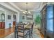 Formal dining room with elegant chandelier, decorative wainscoting and a view into kitchen area at 145 Billowing Sails St, Summerville, SC 29486