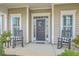 Cozy porch with rocking chairs, potted plants, and decorative wreath, offering a warm welcome at 145 Billowing Sails St, Summerville, SC 29486