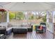 A spacious, covered back porch with a ceiling fan, string lights, comfortable outdoor seating, and wood floors at 1515 Wakendaw Rd, Mount Pleasant, SC 29464