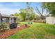 Landscaped backyard featuring a grilling area, fire pit, fenced perimeter, and lush green grass at 1515 Wakendaw Rd, Mount Pleasant, SC 29464