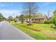 Suburban street featuring a traditional brick home with a green lawn and mature trees at 1515 Wakendaw Rd, Mount Pleasant, SC 29464