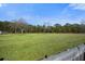 A large, open green field with trees in the background is bordered by a wooden fence in the foreground at 158 Netherfield Dr, Summerville, SC 29486