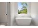 Bright and airy bathroom with a freestanding soaking tub below a window showcasing the exterior at 1615 Macoma Rd, Mount Pleasant, SC 29466