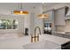 Close-up of a kitchen island with a sink and faucet, pendant lighting, and an open view to the fireplace at 1615 Macoma Rd, Mount Pleasant, SC 29466