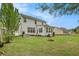 A home's backyard shows a patio with seating, green grass, mature trees, and a fire pit at 176 Hainsworth Dr, North Charleston, SC 29418