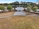 Aerial view of an open air barn with gravel parking, mature trees, and a sprawling green lawn at 183 Country Gate Lane Ln, Summerville, SC 29485