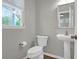 View of a half bathroom with a sleek pedestal sink and a modern toilet, accented by a stylish mirror at 1833 Hubbell Dr, Mount Pleasant, SC 29466