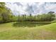 Wide angle backyard view showcasing a serene pond and lush greenery, offering a peaceful retreat at 201 Island Green Rd, Goose Creek, SC 29445