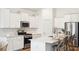 Bright, white kitchen with stainless steel appliances, island with bar seating, and ample cabinet space at 203 Belfort Pl, Summerville, SC 29486