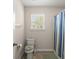Cozy bathroom featuring a toilet, window with blinds, and a shower with a vibrant striped curtain at 210 Sabal Palmetto Ct, Moncks Corner, SC 29461