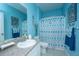 A coastal themed bathroom is styled with blue walls, matching shower curtain, and a large mirror at 2952 Sweetleaf Ln, Johns Island, SC 29455