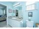 Bright bathroom featuring a vanity with sink, framed mirror, and a toilet, complemented by blue walls at 2952 Sweetleaf Ln, Johns Island, SC 29455