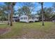 The charming single-story home boasts white brick, complemented by lush green front lawn and swaying palms at 3304 Hartnett Blvd, Isle of Palms, SC 29451