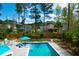 Backyard pool with submerged loungers, fire pit, and lush greenery creates a serene outdoor oasis at 4029 Cascades Thrust, Summerville, SC 29483