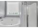 Bathroom with white soaking tub, window with blinds, and glass-enclosed shower at 412 Hydrangea St, Summerville, SC 29483