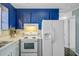 Kitchen with white countertops, white appliances, blue cabinets and dark laminate flooring at 4418 Hardwood St, Ladson, SC 29456