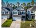 An aerial view of a well-maintained two-story home with a two-car garage, green lawn, and a lush, tree-lined backdrop at 449 Whispering Breeze Ln, Summerville, SC 29486
