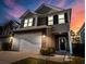 Charming two-story home with stone accents, a two-car garage, a manicured lawn, and inviting curb appeal at twilight at 449 Whispering Breeze Ln, Summerville, SC 29486