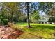 Expansive backyard featuring a manicured lawn, mature trees, and a glimpse of the house at 516 Central Ave, Summerville, SC 29483