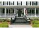 Inviting front porch features classic railing, black stairs, elegant decor, and an American flag at 516 Central Ave, Summerville, SC 29483