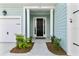 Front door featuring a black door, covered porch, white trim, and well manicured landscaping at 552 Marsh Cv Cir, Summerville, SC 29486