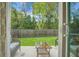 Patio view to fenced backyard, with lush green grass and mature trees for outdoor enjoyment at 7818 Expedition Dr, North Charleston, SC 29420